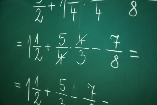 Fraction problems written on a chalkboard