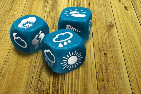 Close up of blue dice with different weather condition symbols on each side