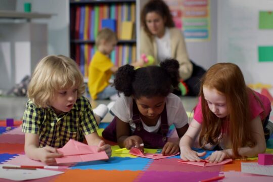 Three young students do an arts and crafts activity.