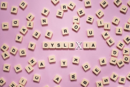 A variety of wooden letter tiles with ‘dyslexia’ spelled in the middle.