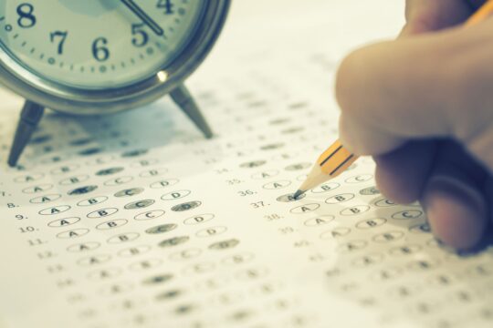 A close-up of a standardized testing answer sheet and a clock.