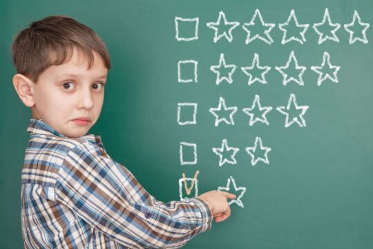 A student points at star ratings written on a chalkboard.