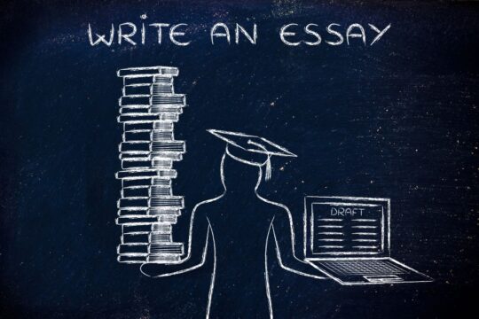 A drawing on a chalkboard of a graduate holding an essay draft on a computer and stack of books.