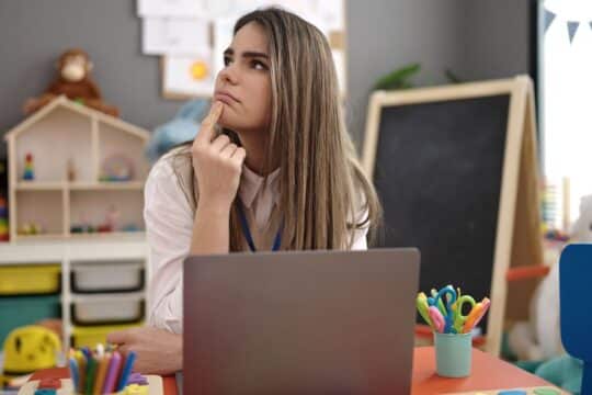 A teacher sits in her classroom representing teaching and learning.
