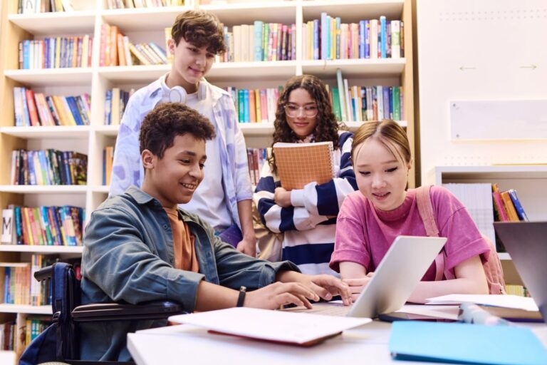 Kids sit around a table in the library working on student projects.