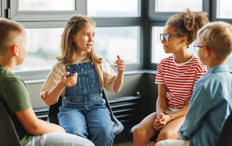 A group of students sit in a circle, having a discussion, representing think, pair, share.