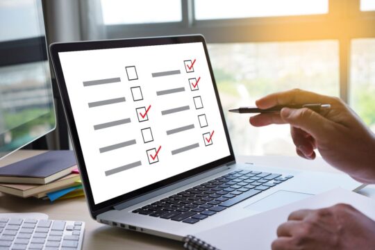 A close-up of someone checking off a list on their laptop, representing electronic gradebooks.