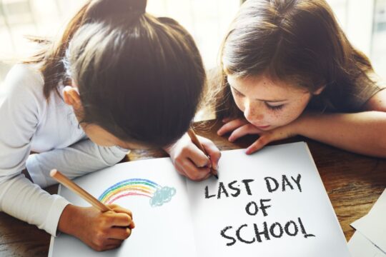 Two students sit at a table drawing a picture for end-of-the-year activities at school.