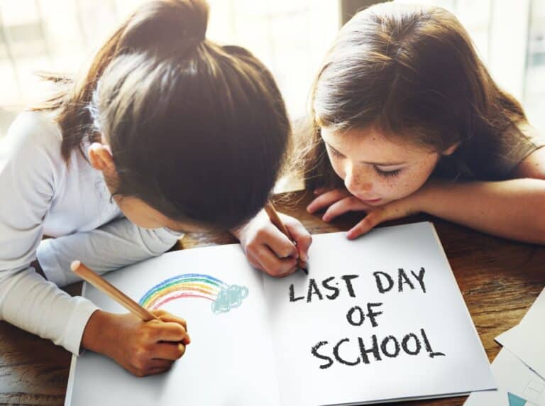 Two students sit at a table drawing a picture for end-of-the-year activities at school.