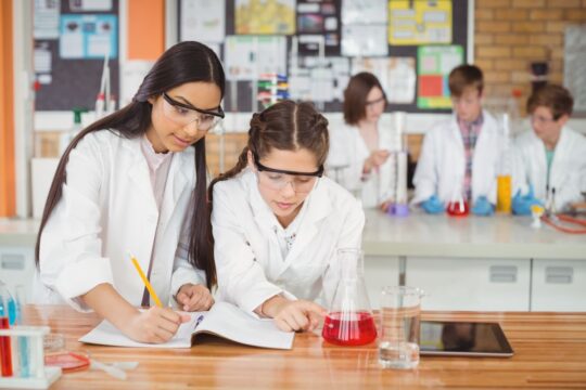 A group of girls are science journaling while they do a science experiment in class.